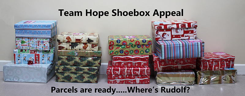 shoeboxes wrapped and stacked with text saying shoeboxes are ready where's Rudolf?